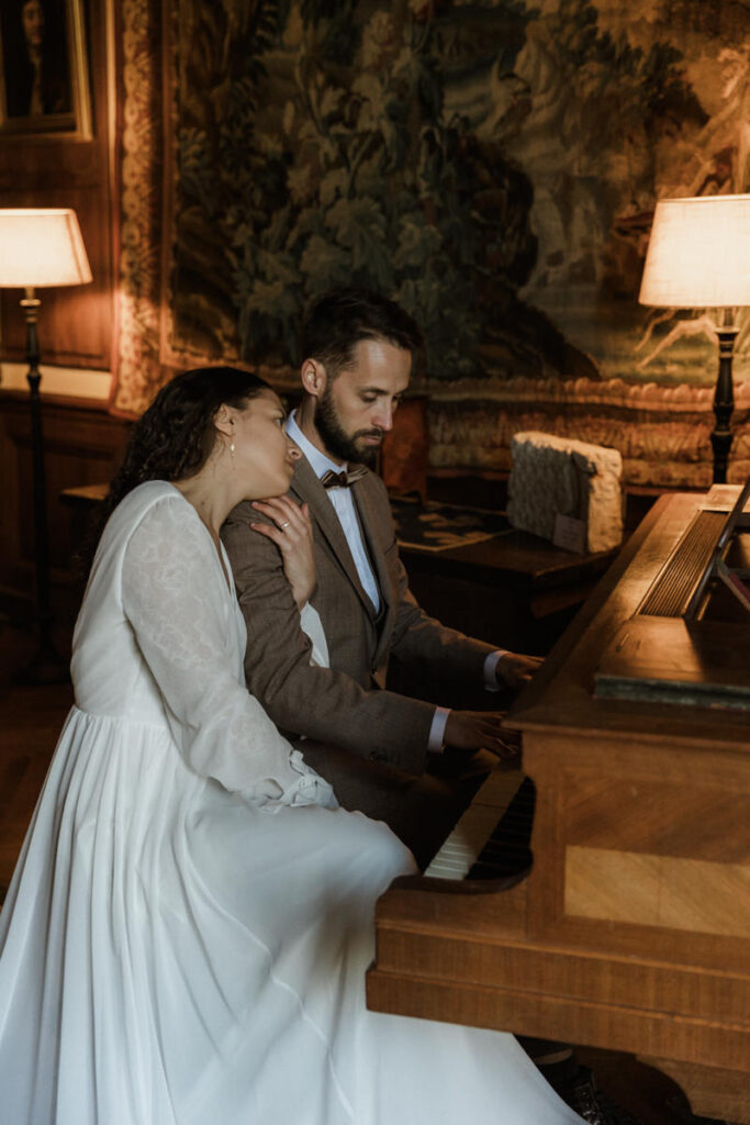 mariés assis au piano dans le salon du château elopement hivernal