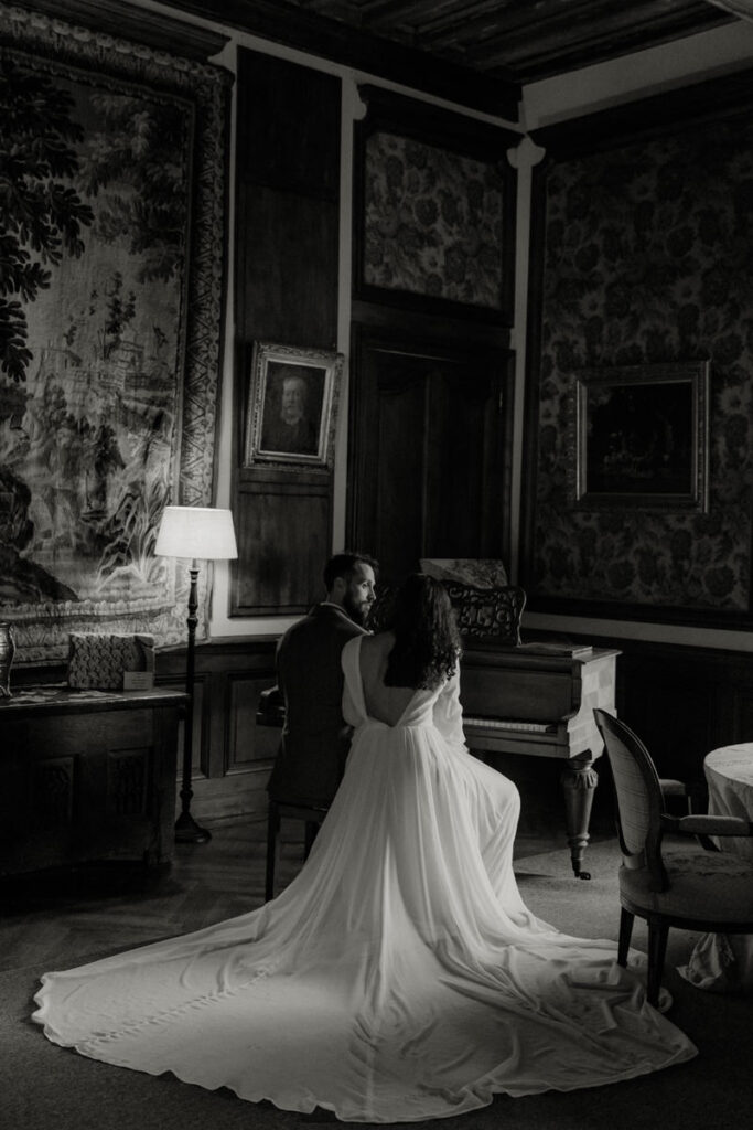 mariés assis au piano dans le salon du château elopement hivernal Pordor